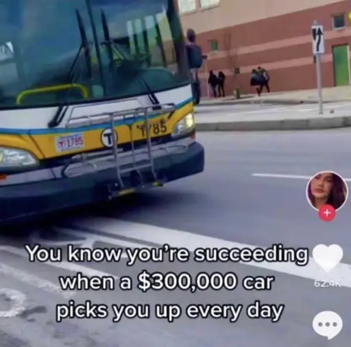 A screencapture of a TikTok video. Pictured is a Massachusetts Bay Transit Authority (MBTA) bus, with a caption that reads 'you know you're succeeding when a $300,000 car picks you up every day'. 
